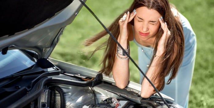 Frustrated woman looking under a car bonnet
